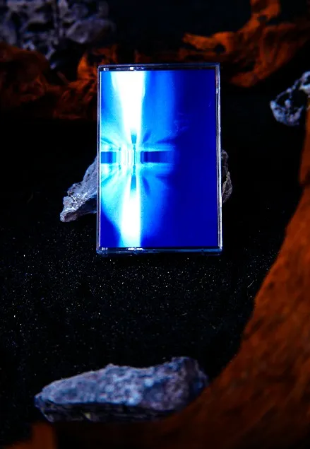 The Normal: the cassette standing on dark sand between driftwood and rock